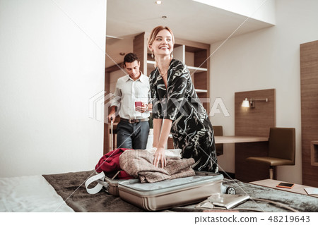 Wife feeling excited taking her clothes out of luggage Wife feeling excited taking her clothes out of luggage 48219643