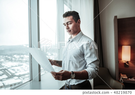 Young ceo holding some documents standing near window 48219870