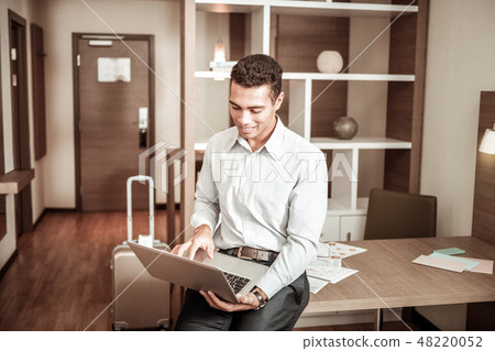 Dark-haired businessman using his laptop while finishing report Dark-haired businessman using his laptop while finishing report 48220052