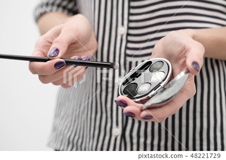 Makeup artist's tools in his hands, mascara, shadows and brush on a white background. Makeup artist's tools in his hands, mascara, shadows and brush on a white background. 48221729