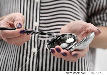 Makeup artist's tools in his hands, mascara, shadows and brush on a white background. Makeup artist's tools in his hands, mascara, shadows and brush on a white background. 48221730