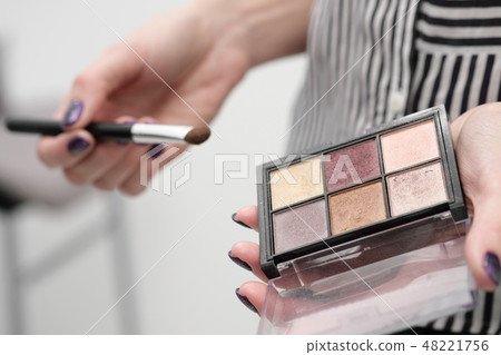 Makeup artist's tools in his hands, mascara, shadows and brush on a white background. 48221756