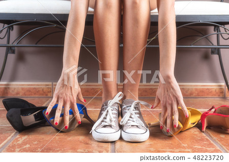 Woman with perfect slim legs, choosing comfortable sneakers rather than uncomfortable high heels 48223720