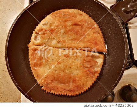 Two appetizing Caucasian chebureks in a pan 48225302