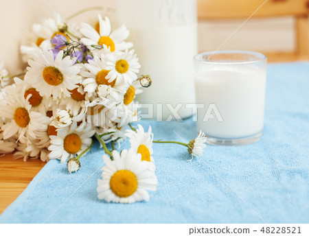 Simply stylish wooden kitchen with bottle of milk and glass on table, summer flowers camomile 48228521