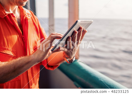chief officer or captain on deck of vessel or ship watching digital tablet 48233125