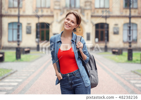 Young student with backpack at university campus standing looking camera cheerful Young student with backpack at university campus standing looking camera cheerful 48238216