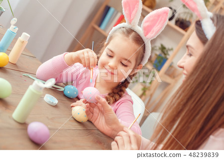 Mother and daughter in bunny ears easter celebration together at home sitting girl making dots with Mother and daughter in bunny ears easter celebration together at home sitting girl making dots with 48239839