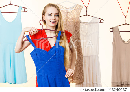 Woman in shop or wardrobe picking dress 48240087