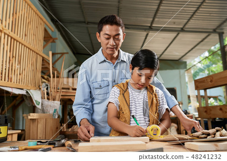 Boy measuring wooden plank Boy measuring wooden plank 48241232