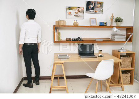Businessman standing in office corner Businessman standing in office corner 48241307