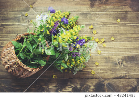 Bouquet of yellow wildflowers in basket on board.  48241485