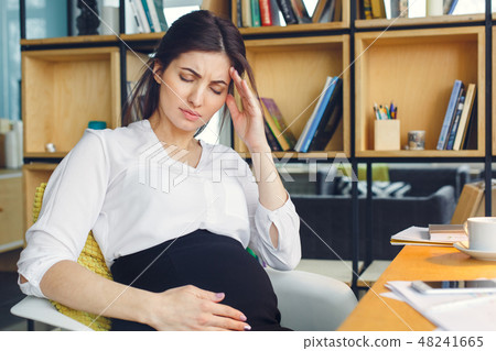Pregnant business woman working at office motherhood sitting feeling unwell Pregnant business woman working at office motherhood sitting feeling unwell 48241665