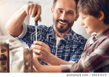 Father and little son at home standing dad screwing screw laughing happy looking at boy holding Father and little son at home standing dad screwing screw laughing happy looking at boy holding 48243523