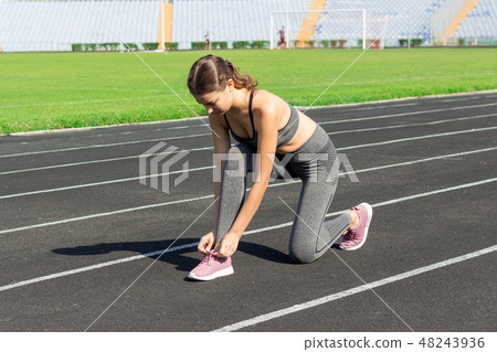 Young woman hands tie laces on her pink sport Young woman hands tie laces on her pink sport 48243936