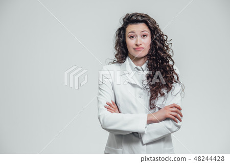 Portrait of happy young smiling girl doctor. Dressed in a white robe. Evenly standing with crossed Portrait of happy young smiling girl doctor. Dressed in a white robe. Evenly standing with crossed 48244428