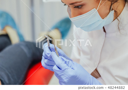 A young wife sits in a dental chair at a doctor's appointment. During this time, she was very 48244882