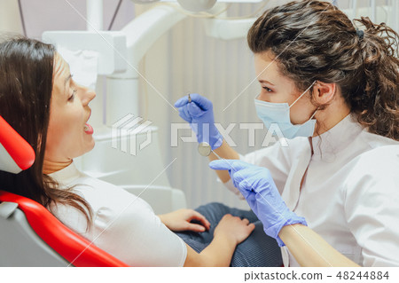 A young wife sits in a dental chair at a doctor's appointment. During this time, she was very 48244884