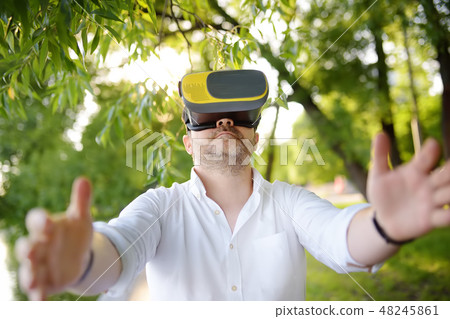 Man using virtual reality headset outdoor.  48245861