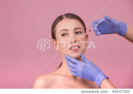 Beautiful woman face and beautician hands with syringe. Doctor makes cosmetic injection in the upper Beautiful woman face and beautician hands with syringe. Doctor makes cosmetic injection in the upper 48247385