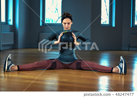 beautiful fit woman in sportswear posing while sitting on the floor with basketball in front of beautiful fit woman in sportswear posing while sitting on the floor with basketball in front of 48247477