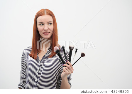Portrait of a red-haired girl, make-up of actor, professional on white background. Paint brushes and Portrait of a red-haired girl, make-up of actor, professional on white background. Paint brushes and 48249805