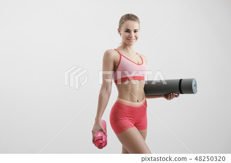 Young athletic woman with an athletic body, wearing wireless headphones and a red sportswear holding Young athletic woman with an athletic body, wearing wireless headphones and a red sportswear holding 48250320