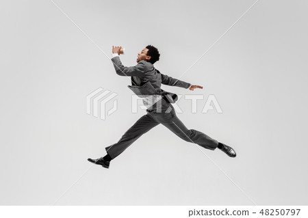 Happy businessman dancing isolated on gray studio background 48250797