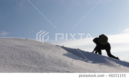 climbers hand in hand climb to top of a snowy mountain. the team of travelers in winter go to their climbers hand in hand climb to top of a snowy mountain. the team of travelers in winter go to their 48251155