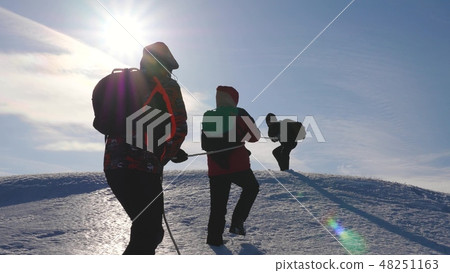three Alpenists climb rope on snowy mountain. Tourists work together as team shaking heights three Alpenists climb rope on snowy mountain. Tourists work together as team shaking heights 48251163