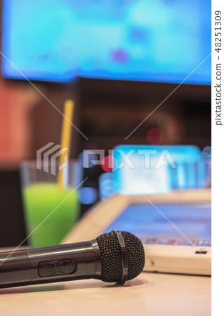 Black microphone of karaoke club, remote control, melon soda drink and television screen. 48251309