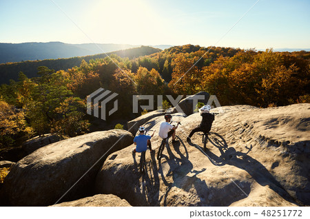 Guys with trial bicycles on the top of mountain at sunset 48251772