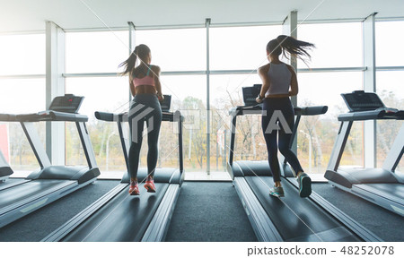 Sports people running on treadmills, looking out the window 48252078