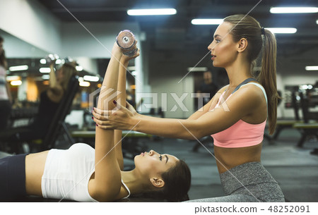 Personal instructor helping woman with chest workout 48252091