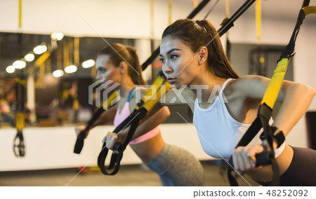 Women training arms with trx fitness straps Women training arms with trx fitness straps 48252092