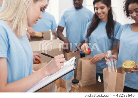 Volunteers putting food and drinks into paper bags 48252646