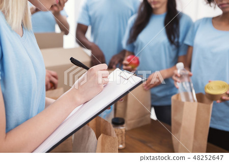 Volunteers putting food and drinks into paper bags 48252647