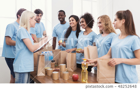 Volunteers putting food and drinks into paper bags 48252648