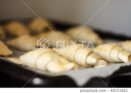 Raw croissants with chocolate on a baking sheet 48253881