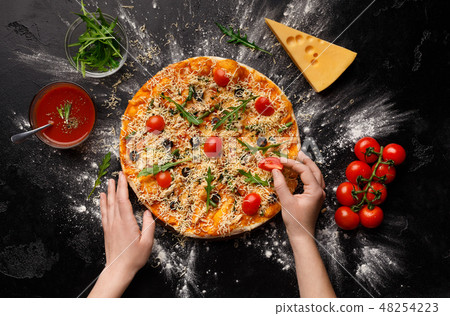 Chef preparing pizza and decorating with cherry tomatoes 48254223