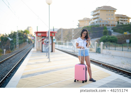 Young Happy Asian Tourist Woman Using Phone At The Train Station Young Happy Asian Tourist Woman Using Phone At The Train Station 48255174