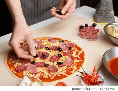 Pizza art. Chef adding olives to pizza Pizza art. Chef adding olives to pizza 48255290