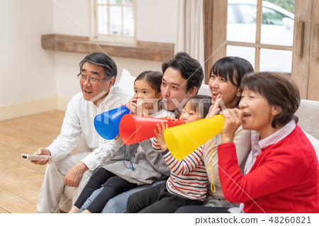 A happy family of three generations who watches TV on a bright living room and supports all six members of the family 48260821