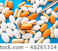 Pills and capsules in spoon on blue background 48265314