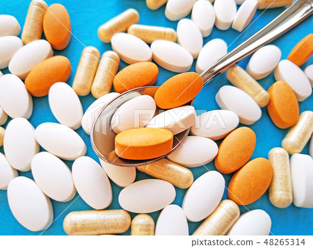 Pills and capsules in spoon on blue background Pills and capsules in spoon on blue background 48265314
