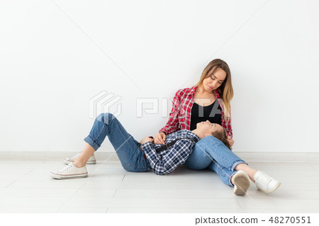 Family, mothers day and teenager concept - Portrait of mother and son sitting on the floor Family, mothers day and teenager concept - Portrait of mother and son sitting on the floor 48270551
