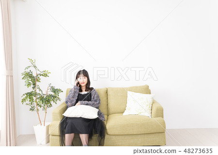 A young woman using a smartphone at home A young woman using a smartphone at home 48273635