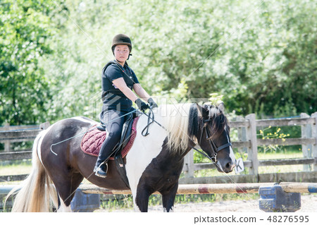 A girl practicing riding on a black and white horse A girl practicing riding on a black and white horse 48276595