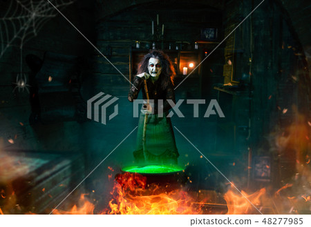 Scary witch cooking potions and reads the spell 48277985