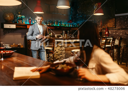 Man lovingly looks on woman at wooden bar counter Man lovingly looks on woman at wooden bar counter 48278006